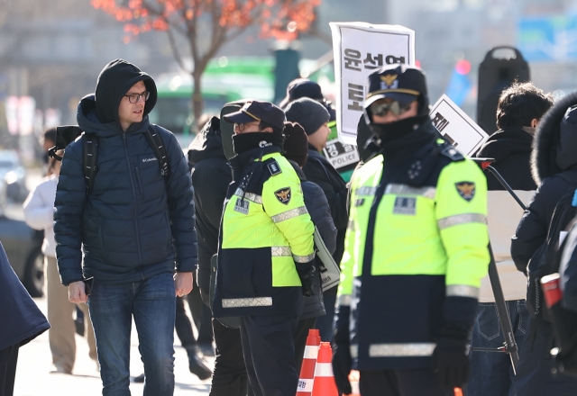 A foreign tourist observes a rally calling for the resignation and impeachment of President Yoon Suk Yeol on Wednesday. (Yonhap)