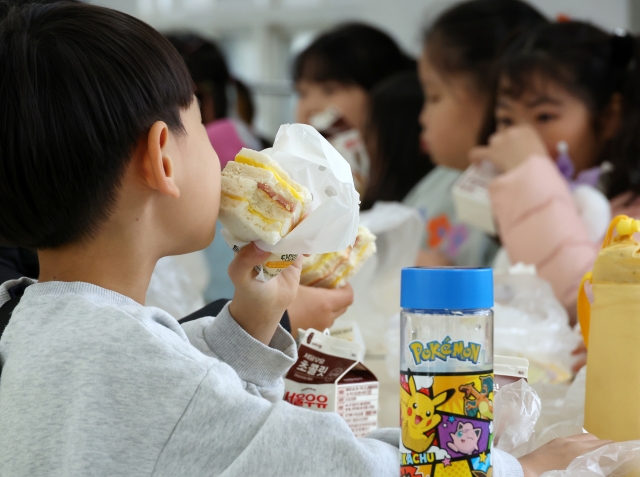 Students at a Busan-based elementary school eat sandwiches and chocolate milk on Friday, which was provided as an alternate lunch after their regular lunch program was disrupted by a day-long strike by school workers. (Yonhap)