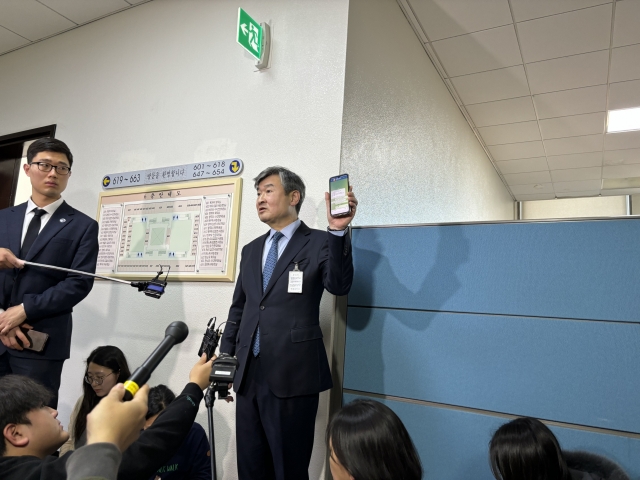 National Intelligence Service Director Cho Tae-yong shows reporters what he explained to be a messenger conversation between him and President Yoon Suk Yeol. (Kim Arin/The Korea Herald)