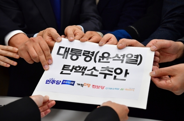 Lamakers of the main opposition parties hold a bill to impeach President Yoon Suk Yeol at the National Assembly in Seoul on Tuesday. (Yonhap)