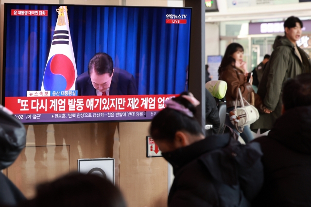 South Koreans at the Seoul Station watches President Yoon Suk Yeol's public address on TV on Saturday. (Yonhap)