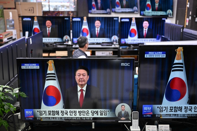 Television screens show live footage of an address by South Korea's President Yoon Suk Yeol, at an electronic market in Seoul on Saturday. (AFP)