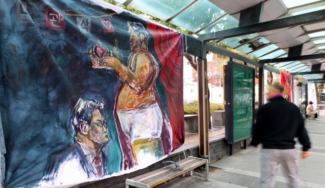 A satirical painting by a young artist depicting President Yoon Suk Yeol and People Power Party leader Han Dong-hoon is displayed on the sidewalk in front of Jeju City Hall on Monday. (Yonhap)