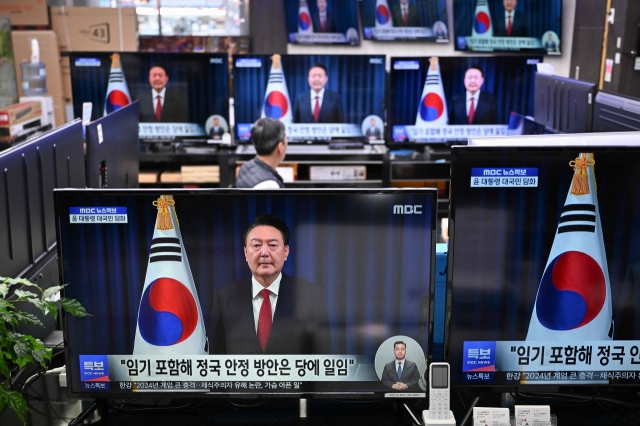 Television screens show live footage of an address by South Korea's President Yoon Suk Yeol, at an electronic market in Seoul on Saturday. South Korean President Yoon Suk Yeol apologised on the day for the confusion caused by his declaration of martial law and said he will let his party decide on his future position. (AFP)