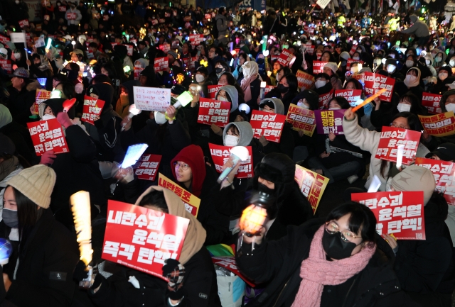 Protesters holding banners and light sticks call for President Yoon Suk Yeol's impeachment and arrest in front of the National Assembly in Seoul on Monday. (Yonhap)