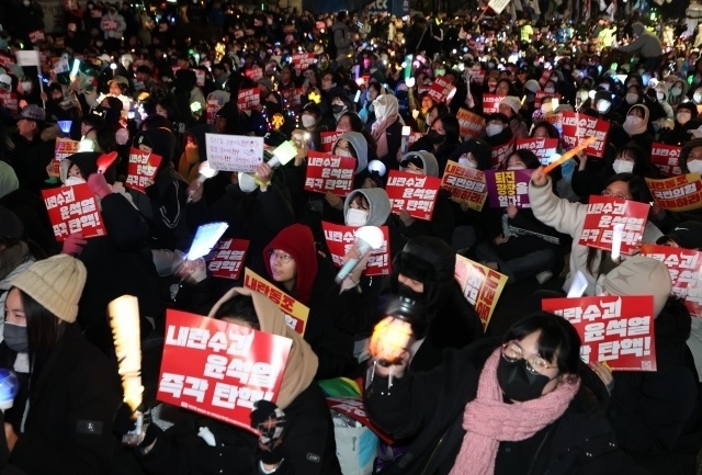 Protesters holding banners and light sticks call for President Yoon Suk Yeol's impeachment and arrest in front of the National Assembly in Seoul on Monday. (Yonhap)