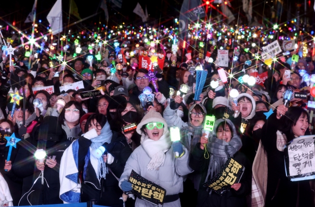 Protesters erupt in celebration in Yeouido after the National Assembly passes the impeachment motion against President Yoon with 204 votes on Saturday. (Yonhap)