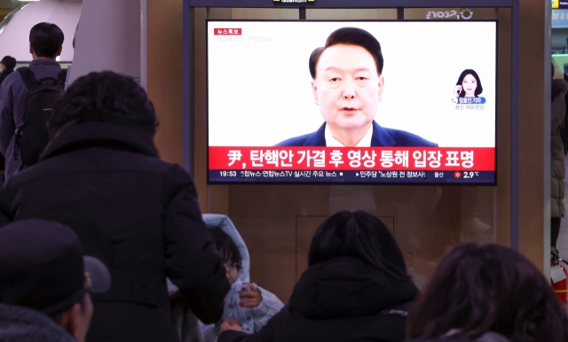 People watch as President Yoon Suk Yeol delivers an address Saturday after the National Assembly voted to impeach him. (Yonhap)