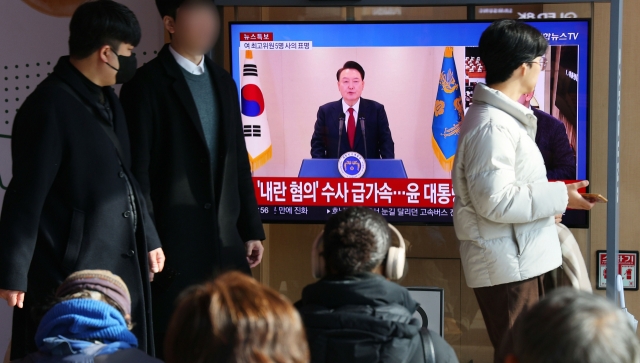 Commuters at Seoul Station watch President Yoon Suk Yeol's public address on TV, Dec. 12. (Yonhap)