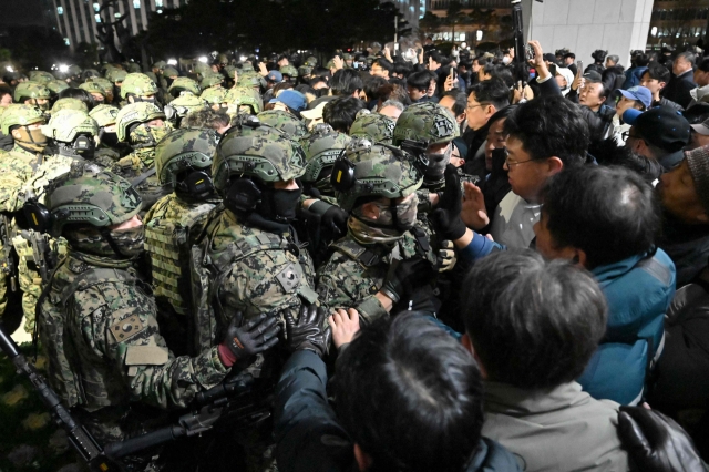 Soldiers try to enter the National Assembly building in Seoul on Dec. 4 after South Korea President Yoon Suk Yeol declared martial law. South Korea's President Yoon Suk Yeol on Dec. 3 declared martial law, accusing the opposition of being 