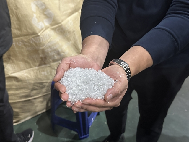 An official from Yuil Industries holds a pile of purified plastic flakes, which can later be used to make other products. (Lee Jung-joo/The Korea Herald)