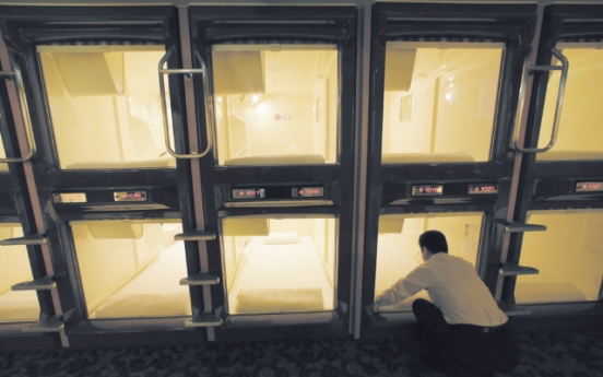 Squeezing into capsule hotel room in Japan