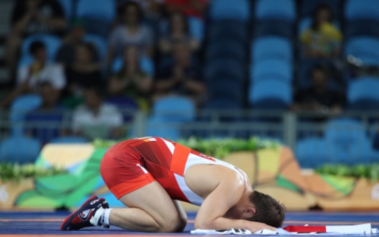 Ex-gold medalist bows out of first round in wrestling