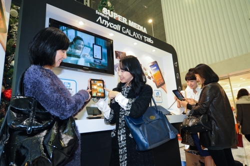 Visitors try Samsung Electronics’ Galaxy Tab in its promotional event at a department store in Seoul on Sunday. (Samsung Electronics)