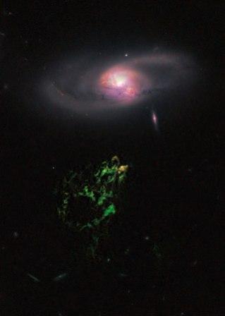 This handout photo provided by NASA, taken April 12, 2010 by the Hubble Space Telescope, shows an unusual, ghostly green blob of gas appears to float near a normal-looking spiral galaxy. (AP-Yonhap News)