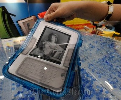 An Amazon Kindle, protected by a special waterproof case, is immersed in water at a consumer electronics show. (AFP-Yonhap News)