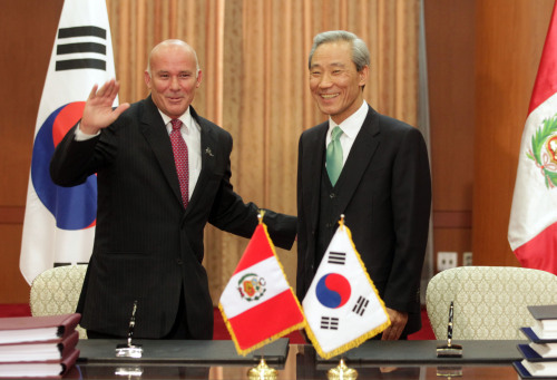 Peruvian Trade Minister Eduardo Ferreyros (left) waves to reporters after he and his Korean counterpart Kim Jong-hoon signed a free trade agreement between the two countries in Seoul on Monday. (Yonhap News)