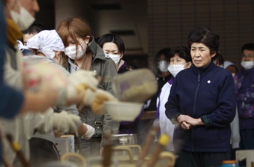 A woman waits for a bowl of soup at an evacuee center Tuesday, in Fukushima, Japan. AP-Yonhap News