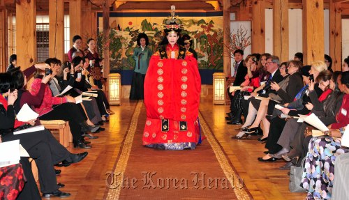 Spouses of foreign ambassadors and other participants watch a fashion show featuring Korean traditional wedding dresses at the Korea Furniture Museum in Seoul on Tuesday. (Kim Myung-sub/The Korea Herald)
