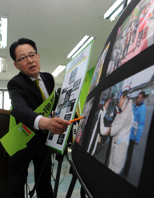 Park Jie-won, floor leader of the main opposition Democratic Party, presents Monday a photograph of Gangwon gubernatorial candidate Ohm Ki-young of the ruling Grand National Party pictured with an alleged organizer of an illicit campaign in Gangneung. (Yonhap News)