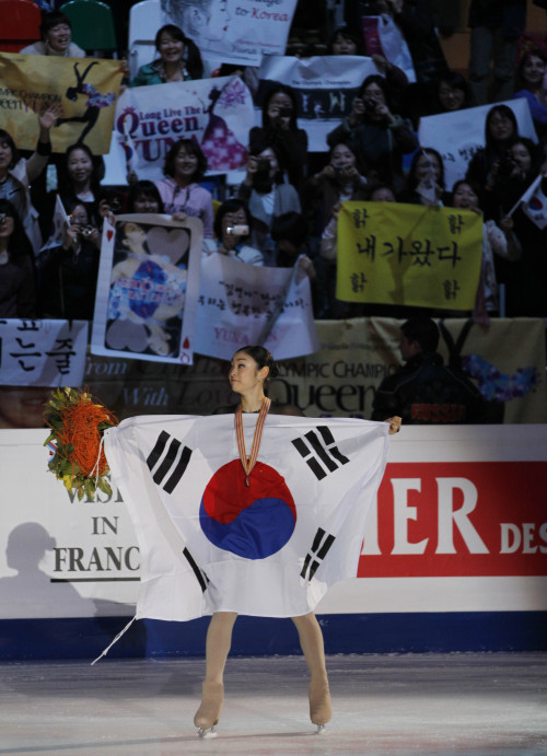 Kim Yu-na carries the national flag after performing her free-skate program. (Yonhap News)