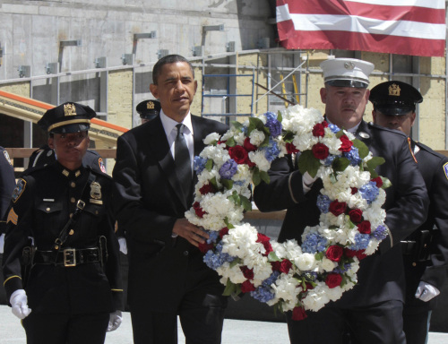 U.S. President Barack Obama, accompanied by a New York City Police officer, New York City Firefighter, and Port Authority officers, carries a wreath to be placed at the World Trade Center site in New York on Thursday. (AP-Yonhap News)
