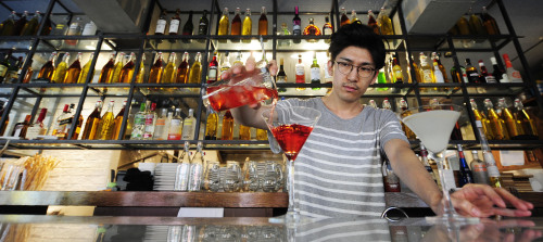 Mixologist Kenneth Lee concocts cocktails at the well-stocked bar of Sofia near Garosugil in Seoul. (Park Hae-mook/The Korea Herald)