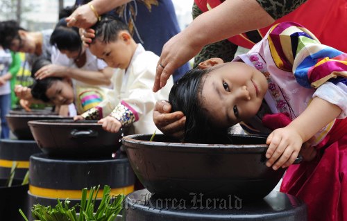 Girls rinse their hair in “changpomul,” or flag iris water Thursday at a festival celebrating Dano in central Seoul. (Park Hae-mook/The Korea Herald)