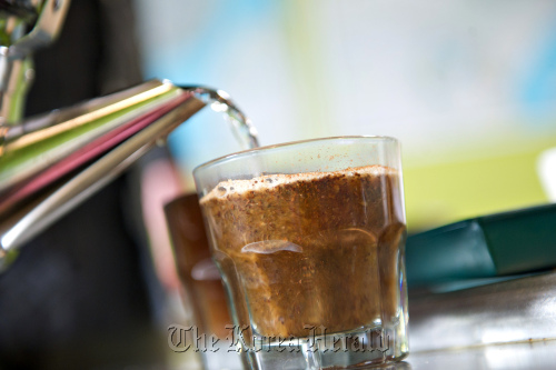 Hot water is poured into a glass of ground Ethiopian coffee. (Bloomberg)