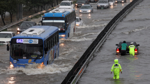 Vehicles wade through a water-logged road in Yeouido, Seoul, as heavy rains drenched the central part of the country on Wednesday. (Yonhap News)