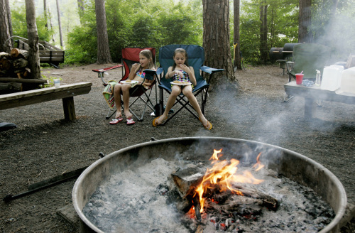 Nora McNabb, 8, left, and Rachel Laskowski, 9, eat dinner near the campfire during an annual multiple family camping trip at Falls Lake Shinleaf Campground, June 10, in Raleigh, NorthCarolina. (Raleigh News & Observer/MCT)