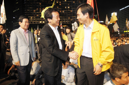 DP leader Sohn Hak-kyu (left) greets Rhyu Si-min, chairman of the People’s Participation Party, at the progressives’ rally Saturday in Seoul Plaza against Hanjin Heavy Industries and Construction Co. layoffs. (Yonhap News)
