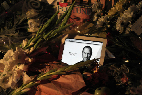 Apple products and flowers are seen on a makeshift shrine following the death of Steve Jobs at Apple headquarters Wednesday. (AP-Yonhap News)