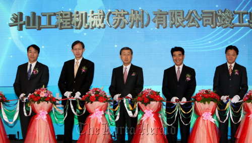 Doosan Group chairman Park Yong-hyun (center), Doosan Infracore Co. president and chief executive Kim Yong-sung (far left), the Suzhou Industrial Park Administrative Committee’s director Yang Zhiping (far right) and other officials cut the tape at a ceremony to mark the completion of the Korean firm’s plant in Suzhou, China to manufacture excavators on Wednesday. (Doosan Infracore Co.)