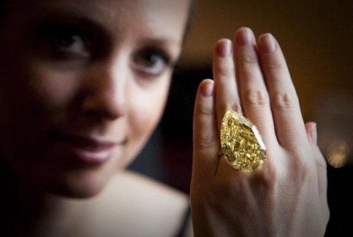 A model displays a 110.03 carats Sun-Drop Diamond described as fancy vivid yellow, the highest color grading, by gemstone experts, at a Sotheby`s preview show in Geneva, Switzerland. (AP)