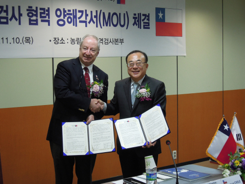 Anibal Ariztia (left) and Park Young-ho, heads of the Chilean and Korean animal quarantine services, hold up the agreement they signed in Anyang this month. (Embassy of Chile)