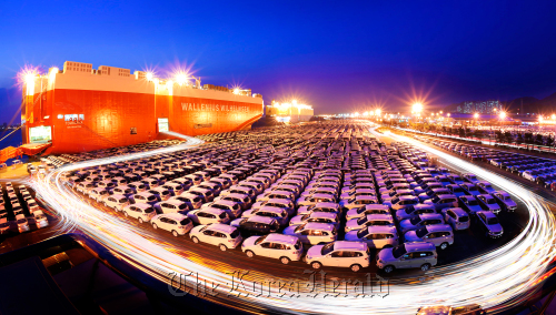 Cars bound for export are loaded onto a transporter ship in Ulsan. (The Korea Herald)