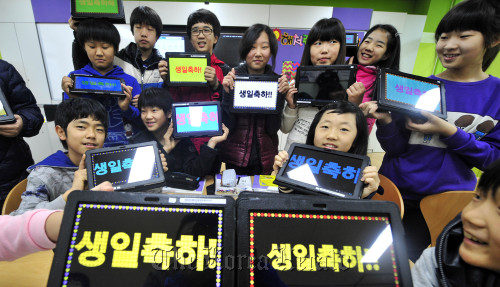 Students at Chamsaem Elementary School, one of the four schools that opened in Sejong City on Friday, hold tablet PCs that read “Happy Birthday (to the school).” (Kim Myung-sub/The Korea Herald)