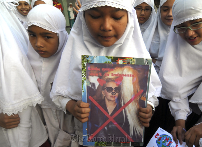 A Muslim elementary school student holds a defaced poster of U.S. pop singer Lady Gaga during a protest against her concert in Solo, Central Java, Indonesia. (AP-Yonhap News)