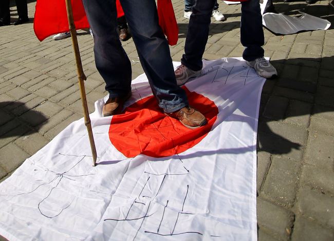 Anti-Japan protesters stand on a Japanese flag in Shanghai, China, Sunday. (AP-Yonhap News)