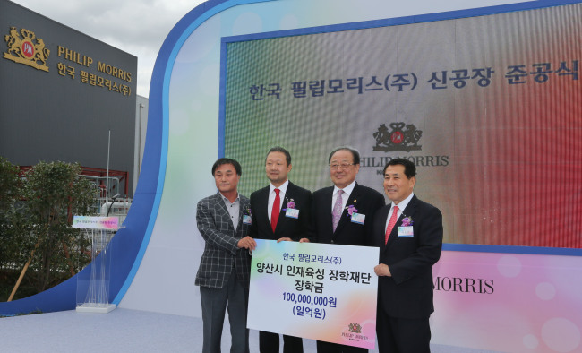 Chong Il-woo (second from left), managing director of PMKI, delivers 100 million won in scholarship funds to a charity foundation during the opening ceremony for its new plant in Yangsan, South Gyeongsang Province, Monday. (Philip Morris Korea)