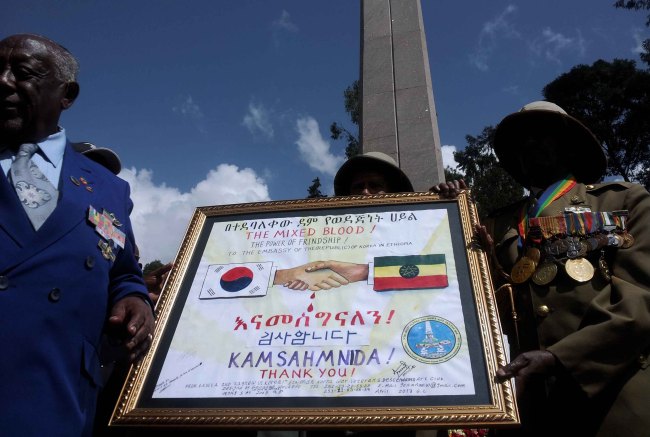 Ethiopian Korean War veterans hold a framed commemoration poster during an event held in Addis Ababa, Ethiopia, Saturday, to reenact Ethiopian troops’ departure for South Korea to fight the war. (Yonhap News)