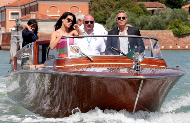 U.S. actor George Clooney (right) steers a boat next to actress Sandra Bullock before a photocall for the movie “Gravity,” presented out of competition on the opening day of the 70th Venice Film Festival on Wednesday at Venice Lido. (AFP-Yonhap News)