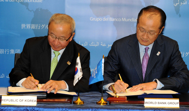 Finance Minister Hyun Oh-seok (left) and World Bank president Jim Yong Kim sign an agreement at the World Bank’s headquarters in Washington D.C. on Thursday for the opening of a regional office of the World Bank in Songdo, west of Seoul, in December. (Yonhap News)