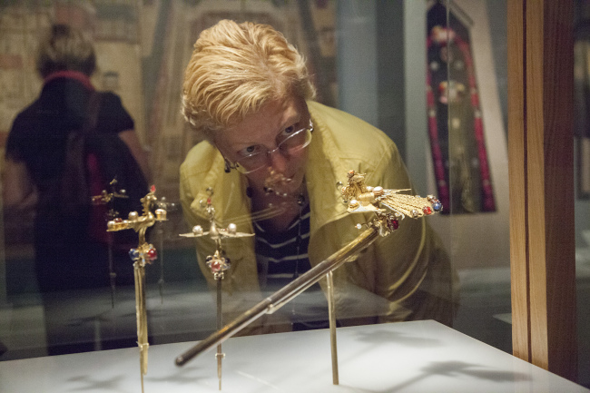 A visitor views ceremonial hair ornaments on display at the Asian Art Museum. (Asian Art Museum)