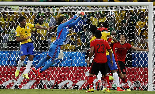 Brazil's Paulinho (8) watches as Mexico's goalkeeper Guillermo Ochoa punches the ball clear of the goal during the group A World Cup soccer match between Brazil and Mexico at the Arena Castelao in Fortaleza, Brazil, Tuesday, June 17, 2014. (AP-Yonhap)
