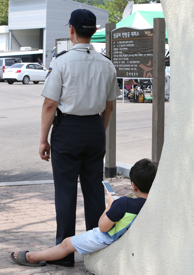 A child uses his mobile phone outside an underground evacuation shelter guarded by police in Yeoncheon, Gyeong Province, Sunday. (Yonhap)