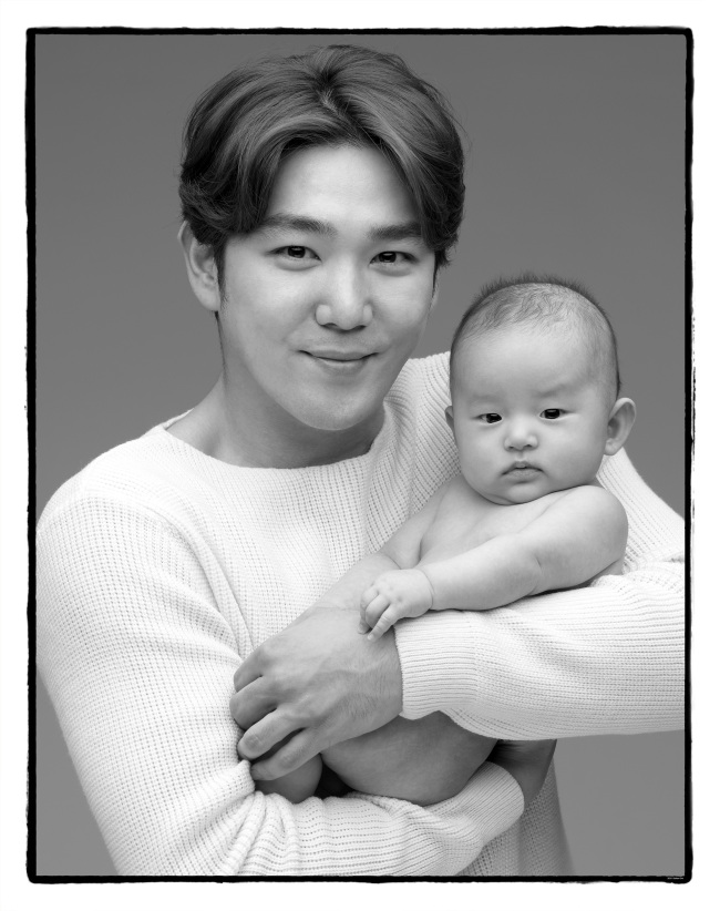Kangin of Super Junior poses with a baby. (Photo by Cho Seihon)