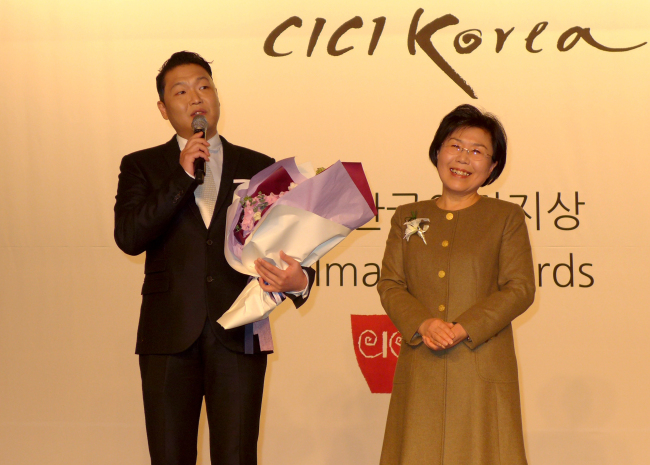 Korean singer Psy (left) accepts the Korea Image Stepping Stone Award from Choi Jung-wha, president of the Corea Image Communications Institute, at the annual award ceremony reception at Intercontinental Seoul Coex on Tuesday. (Joel Lee/The Korea Herald)