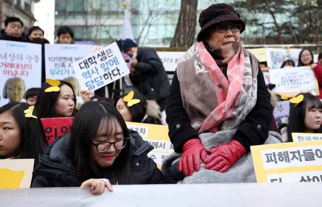 Sex slavery victim Lee Yong-su embraces the hand of a student participating in a rally in front of the Japanese Embassy in Seoul on Wednesday. Yonhap
